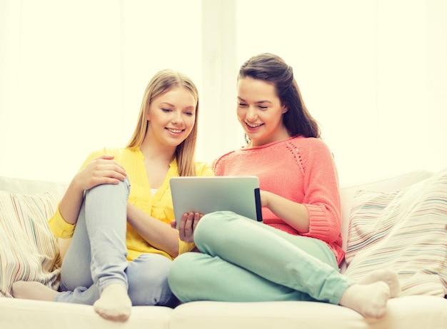 amistad, tecnología y concepto de internet - dos adolescentes sonrientes con una computadora de tablet pc en casa