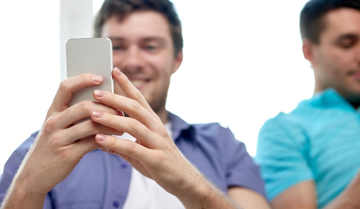 Foto amistad, tecnología y concepto de personas: cerca de amigos sonrientes felices con teléfonos inteligentes que envían mensajes de texto en casa
