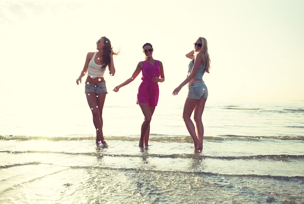 amistad, vacaciones de verano, fiesta, felicidad y concepto de la gente - grupo de amigas felices bailando en la playa