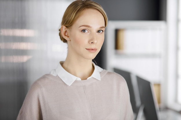 Amistosa mujer de negocios vestida casualmente para adultos o una estudiante de pie recta. Foto de negocios o retrato en la oficina.