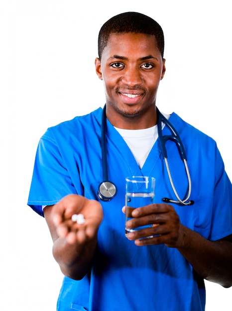 Amistoso médico africano en matorrales con pastillas y vaso de agua mirando a la cámara