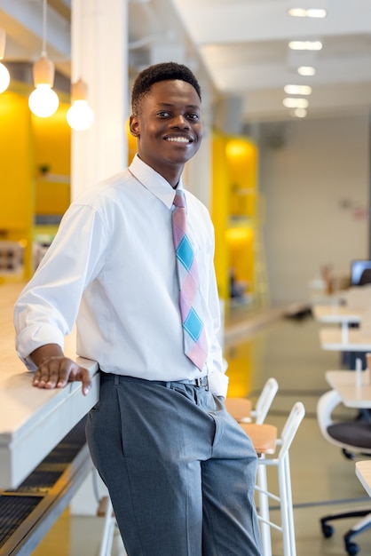 Amistoso y sonriente joven empresario profesional afroamericano mirando a la cámara en la oficina moderna
