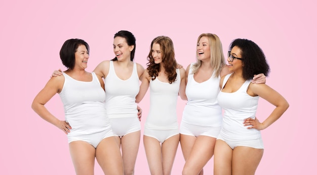 amizade, beleza, corpo positivo e conceito de pessoas - grupo de mulheres felizes diferentes em cueca branca sobre fundo rosa