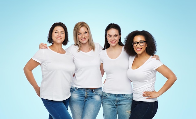 Amizade, diversidade, corpo positivo e conceito de pessoas - grupo de mulheres felizes de tamanho diferente em camisetas brancas abraçando sobre fundo azul