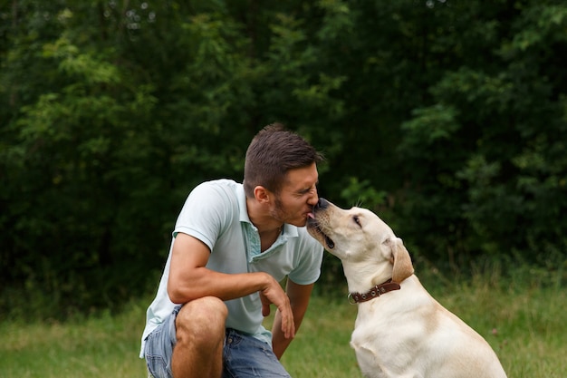 Amizade e amor de homem e cachorro. Jovem feliz beijando com seu amigo