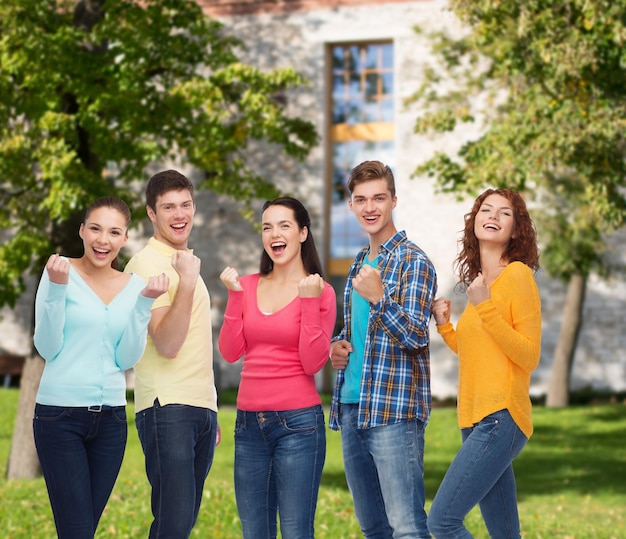 amizade, educação, férias de verão, trabalho em equipe e conceito de pessoas - grupo de adolescentes sorridentes mostrando gesto de triunfo sobre o fundo do campus