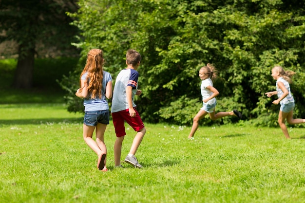 amizade, infância, lazer e conceito de pessoas - grupo de crianças felizes ou amigos jogando jogo de recuperação e correndo no parque de verão