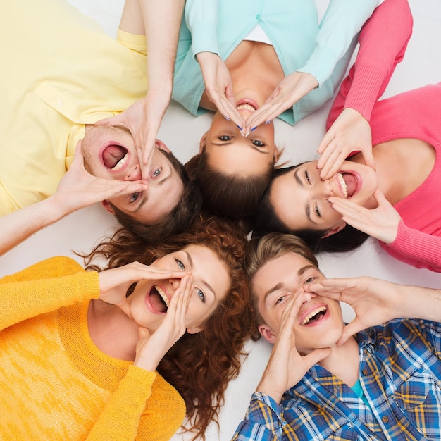 amizade, juventude, gesto e pessoas - grupo de adolescentes sorridentes deitados no chão em círculo e gritando