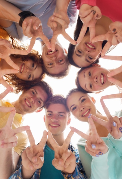 amizade, juventude, gesto e pessoas - grupo de adolescentes sorridentes em círculo mostrando sinal de vitória