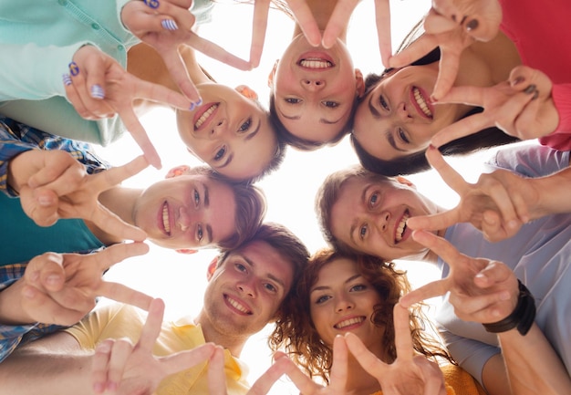 amizade, juventude, gesto e pessoas - grupo de adolescentes sorridentes em círculo mostrando sinal de vitória