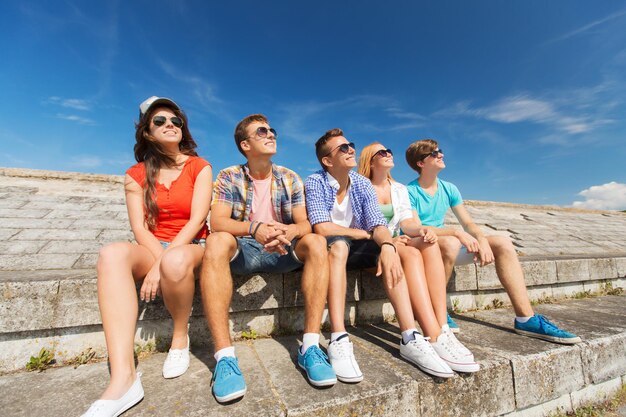 amizade, lazer, verão e conceito de pessoas - grupo de amigos sorridentes sentados na rua da cidade