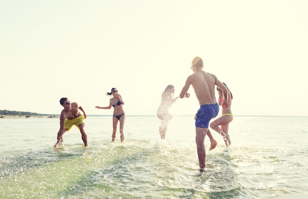 amizade, mar, férias de verão, feriados e conceito de pessoas - grupo de amigos felizes se divertindo na praia de verão
