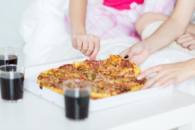 amizade, pessoas, festa do pijama e conceito de junk food - close-up de amigos ou adolescentes comendo pizza em casa