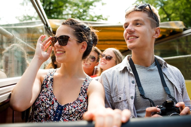 amizade, viagens, férias, verão e conceito de pessoas - casal sorridente com câmera viajando de ônibus de turismo