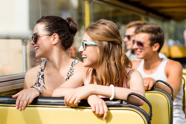 amizade, viagens, férias, verão e conceito de pessoas - grupo de amigos sorridentes viajando de ônibus de turismo