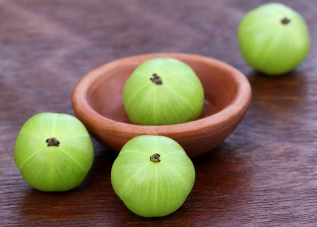 Amla fresca com uma tigela pequena na superfície de madeira