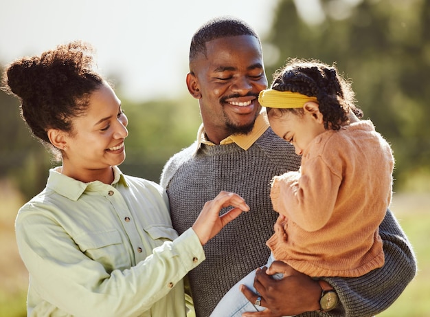 Amo a família e a garota feliz com os pais em um parque rindo e brincando enquanto se unem na natureza Amo a família feliz e a criança relaxa, brinca e aproveita o tempo de qualidade com a mãe e o pai em uma floresta