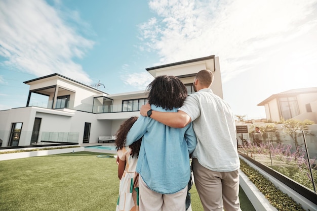 Amo a nova casa e a família em pé no quintal olhando para sua propriedade ou imóveis de luxo Abrace a hipoteca e os pais com seus filhos na grama em sua casa ou mansão no Canadá