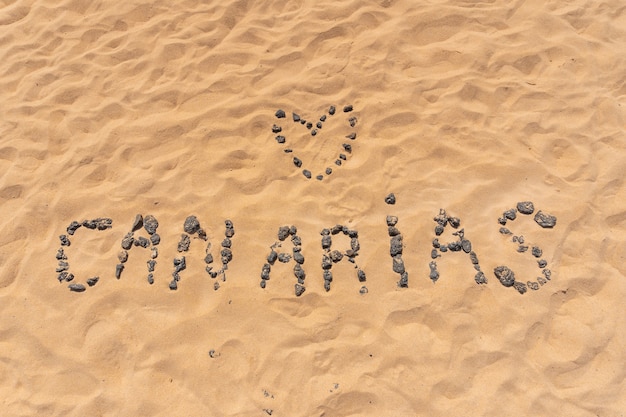 Amo las Islas Canarias con piedras negras en la playa de las dunas del Parque Natural de Corralejo, Fuerteventura, Islas Canarias. España