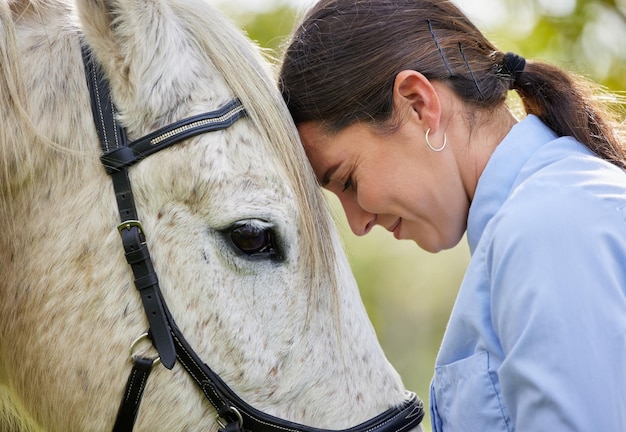 Amo a mi caballo Disparo de una mujer joven y atractiva parada con su caballo en un bosque