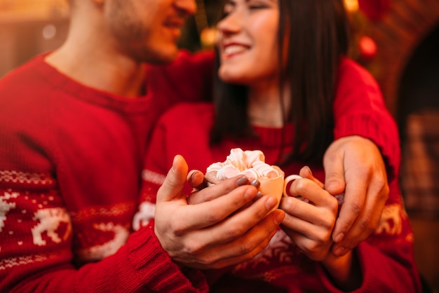 Amo o casal de mãos quentes em uma xícara de café, romântica celebração de Natal. Férias de Natal, homem e mulher felizes juntos, decoração festiva