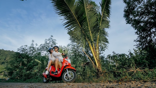 Amo o casal na moto vermelha em roupas brancas para fazer uma viagem de trilha florestal dois turistas caucasianos