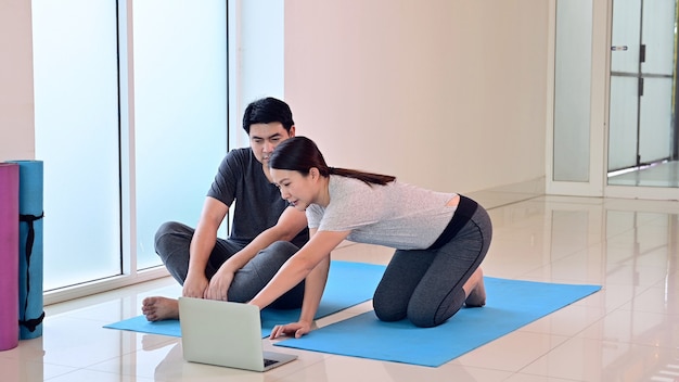 Amo o casal online aprendendo ioga, respiração e meditação juntos em casa. esporte e exercício para uma saúde saudável. estilo de vida asiático da mulher e do homem.