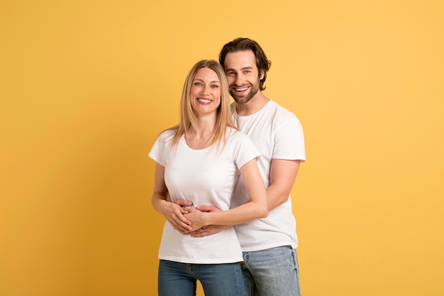 Amo relacionamento familiar e romance Sorrindo jovem homem caucasiano abraçando mulher em camisetas brancas