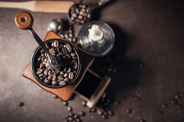 Amoladora de café y grano de café hermosos en viejo fondo de la tabla de cocina.