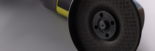 Amoladora de sierra eléctrica con boquilla en la superficie gris Imagen detallada de una poderosa herramienta de sierra circular