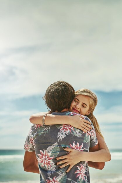 Foto el amor está en el aire captura recortada de una joven pareja cariñosa abrazándose en la playa