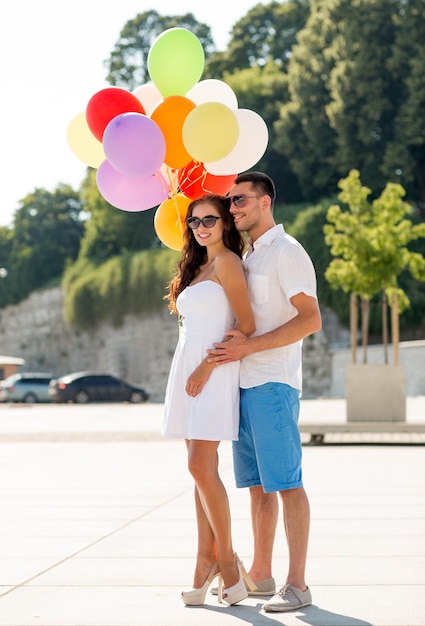 amor, casamento, verão, namoro e conceito de pessoas - casal sorridente usando óculos escuros com balões abraçando no parque