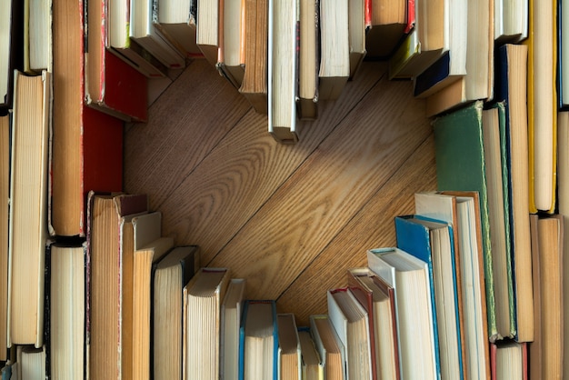 Amor concepto de forma de corazón de viejos libros antiguos sobre fondo de piso de madera. Composición de estilo de tono de color vintage de amor con forma de corazón de libro abierto