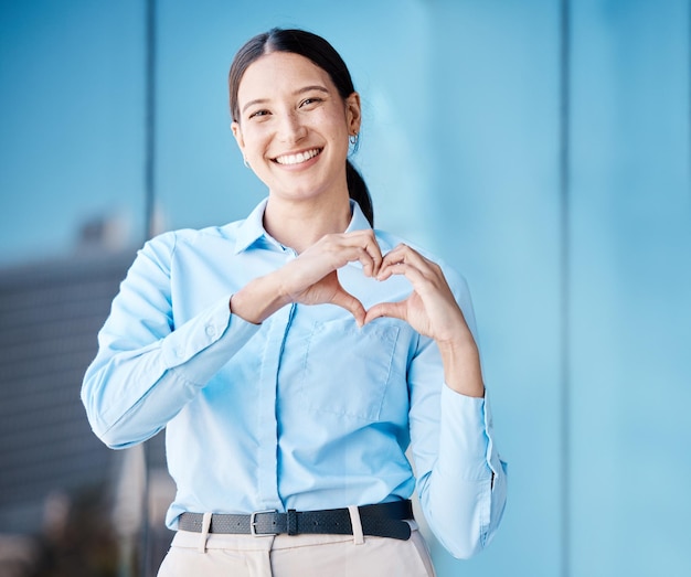 Amor del corazón y salud con las manos de una mujer de negocios haciendo un gesto con una sonrisa afuera en la ciudad Retrato de una empleada corporativa que muestra afecto y está sola al aire libre