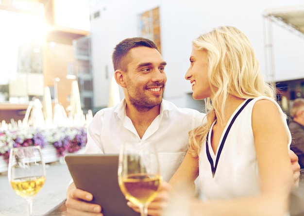 amor, data, tecnologia, conceito de pessoas e relações - sorrindo casal feliz com computador tablet pc no terraço do restaurante