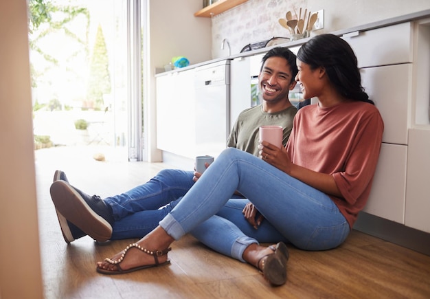 Amor de comunicação de casal com café na cozinha e feliz juntos para se relacionar pela manhã Homem e mulher na Índia no chão sorriem enquanto conversam, romance e relacionamento saudável