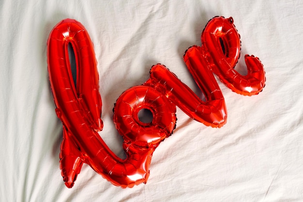 Amor de letras vermelhas para festa dia dos namorados e mãos na cama, vista superior.