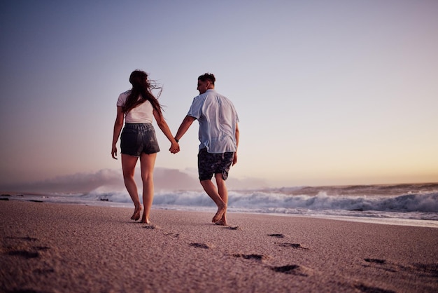 Foto amor de mãos dadas e casal caminhando na praia relaxam vínculos e desfrutam de momentos românticos de qualidade juntos em israel paz liberdade e ar do oceano para homem e mulher na areia do mar viagem para bem-estar calma