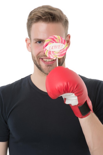 Foto amor deporte hombre sonriente cara feliz sostener piruleta guante de boxeo alimentos saludables dieta boxer dulces trampa comida dieta deportiva y calorías azúcar y nutrición deportiva boxeador contra dulce seducción