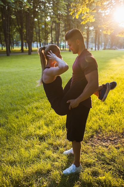 Amor deportista pareja apoyo entrenamiento concepto al aire libre. ejercicios para los abdominales. romance de gente activa.