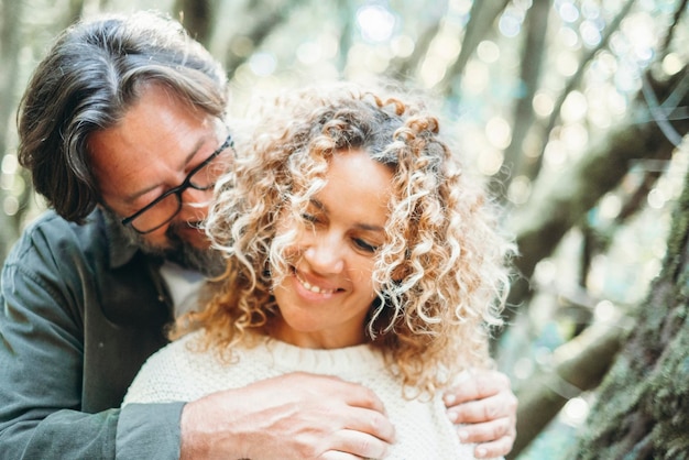 Amor e romance em atividade de lazer ao ar livre com homem e mulher apaixonados abraçando e se unindo ao ar livre com fundo de floresta de árvores verdes Pessoas românticas casal heterossexual sorrindo juntos Sussurros