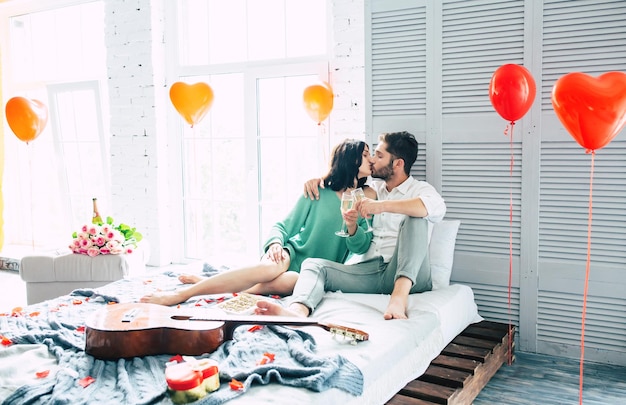 Amor em cada momento. Lindo casal lindo está abraçando, beijando e relaxando enquanto comemoram o dia de São Valentim em casa