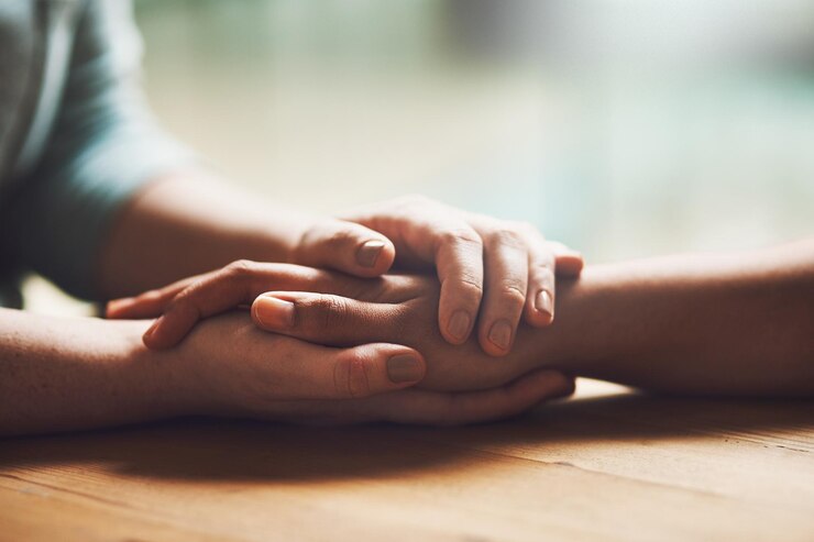 Foto amor empatia e apoio com pessoas de mãos dadas em conforto, cuidado ou compreensão em uma mesa de madeira de uma casa oração fé ou depressão com amigos próximos para hep esperança ou paz para cura