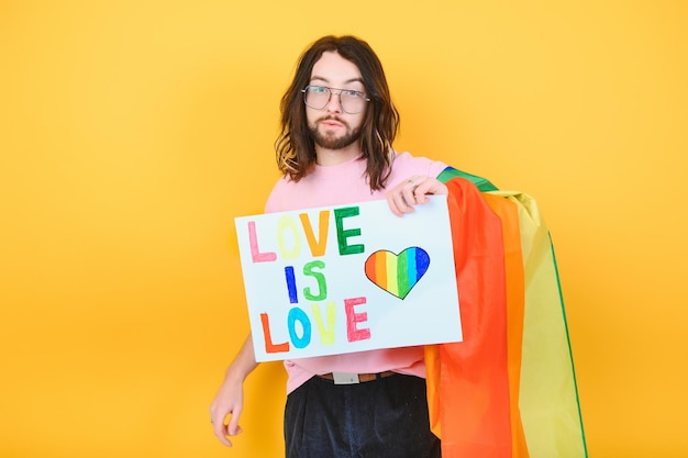 El amor es amor Atractivo hombre caucásico gay sosteniendo un cartel de protesta durante un desfile del orgullo LGBT