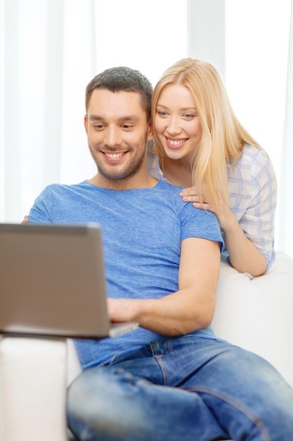 amor, familia, tecnología, internet y concepto de felicidad - pareja feliz sonriente con computadora portátil en casa