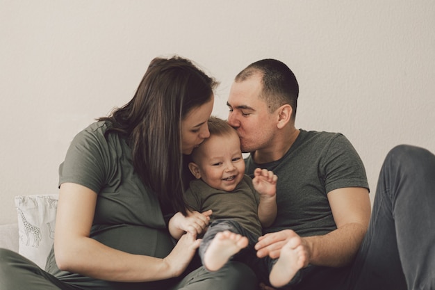 Amor familiar. Los padres y el hijo pequeño, divirtiéndose juntos en casa en el dormitorio.