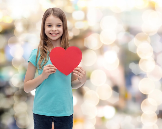 el amor, la felicidad y el concepto de la gente - niña sonriente con el corazón rojo