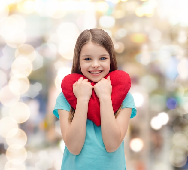 el amor, la felicidad y el concepto de la gente - niña sonriente con el corazón rojo