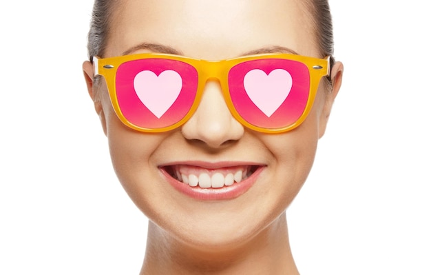 amor, felicidad, día de san valentín, expresiones faciales y concepto de personas - retrato de una adolescente sonriente con gafas de sol rosas con corazones