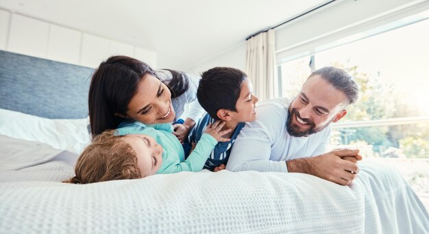 Foto amor feliz y familia jugando juntos en la cama en el dormitorio de su casa moderna felicidad emocionada y niños divirtiéndose jugando y uniéndose con sus padres en una habitación en casa